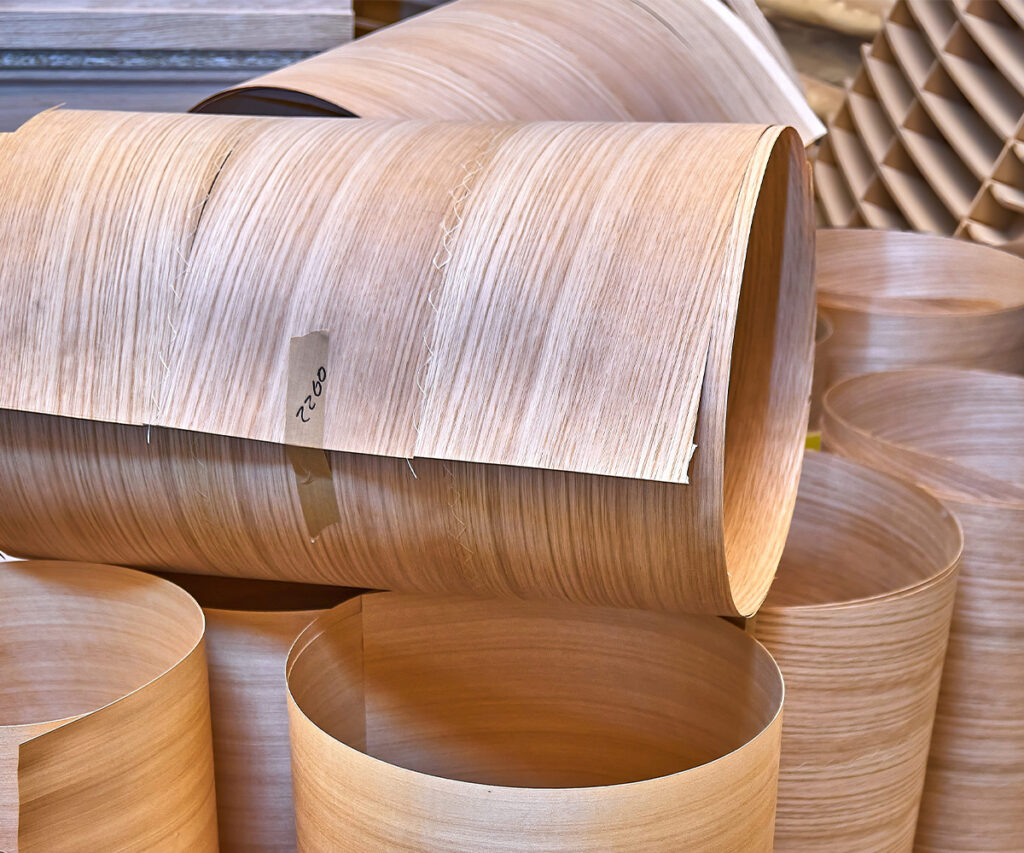 Rolled wood veneer sheets stacked in a furniture manufacturing shop.