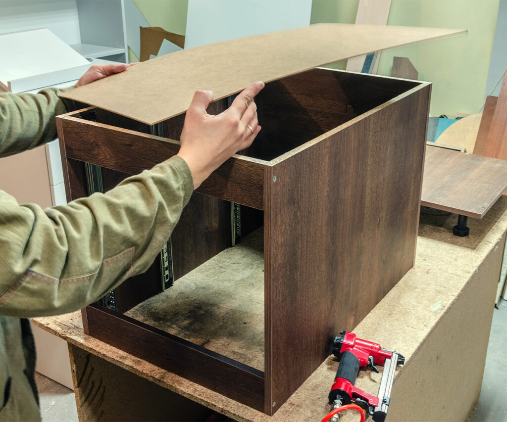 Assembling a laminated cabinet box with a particleboard top panel.